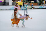 Fototapeta  - oman teaches a girl figure skating on ice.