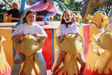 Fototapeta  - Teenage girls ride on carousels in the park.