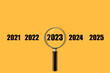 2021. 2022.2023.2024.2025. Number and magnifying glass, on an orange background. New Year concept. copy space. Christmas