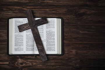 Holy bible on a wooden surface. Wooden cross on the bible. Free space for text. Christian picture. The texts in the book are in Russian.