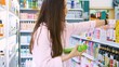 © ShantiMedia - A woman with long hair chooses a shampoo and balm for hair restoration. Buying shampoo in the store. Choosing a good shampoo for hair restoration and for daily use. Buying cosmetics for a woman.