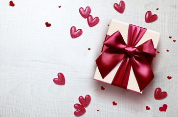 Wall Mural - Top view photo of valentine's day decorations white gift box with red ribbon bow and small hearts on isolated grey background.