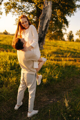 Wall Mural - vertical portrait of unrecognizable loving young man holding cheerful redhead woman in arms on green