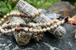 A close up image of three healing smudge sticks with wooden mala beads.