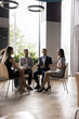 © fizkes - Workflow of business team in modern office room, vertical image. Five businesspeople, employees listening to female coach or business trainer during briefing or seminar gathered in modern workspace