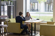 © fizkes - Two colleagues talking seated at table in office. Female applicant passes job interview during appointment with HR manager answers questions communicating in modern office workspace. Business meeting