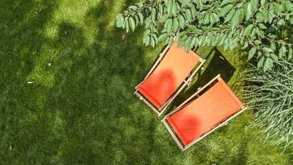 Summer garden with sunbed deckchairs on grass aerial top view, green park trees and place for relax from above
