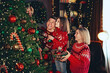 © ZaStock - Happy Christmas family mother father and daughter decorated Christmas tree in living room. New Year