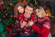 © ZaStock - Happy family mom dad and daughter hugging near Christmas tree over decorated living room