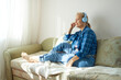© evafesenuk - Mature woman in blue headphones relaxing on the couch listening to music