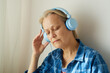 © evafesenuk - Close-up pensioner woman listening to music in headphones, relaxing at home