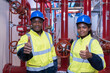 © amorn - Portrait of two engineer working at system springer prevent fire. Group of African American contractor checking fire sprinkler system, pipe assembly, red fire pipe