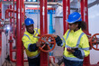 © amorn - Two engineer or technician maintenance, checking, or test system springer prevent fire. Group of African American contractor checking fire sprinkler system, pipe assembly, red fire pipe