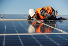 A Worker Is Looking At Solar Panels And Checking If They Are Straight.