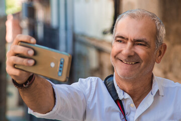 Wall Mural - mature happy man with phone taking a selfie or live video