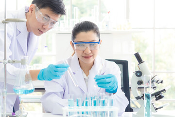 Wall Mural - team work asian woman and man scientists analyzing study data and evaluating microscope success for 