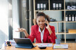 © Nuttapong punna - Business woman Talking on the phone and using a laptop with a smile while sitting at office..