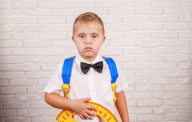 Happy boy with down syndrome holds a protractor ruler in his hands, early development, preparation for school, visual aid for teaching geometry at school.
