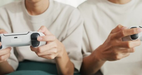 Canvas Print - Close-up Young Asian couple sit on couch hold joystick play video game spend time together have fun at home on weekend. Happy husband and wife laugh relax with online game, Lifestyle activity concept.