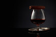 Snifter of brandy and cigar on a black background.