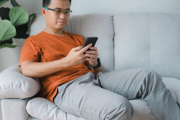 Aufkleber - Happy smiling man using smartphone device while chilling on sofa a home, cheerful hipster guy typing an sms message