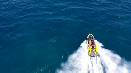 Wall Mural - Aerial drone video of jet ski watercraft operated by stunt man speeding in deep blue open ocean sea