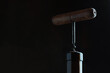 Corkscrew and cork. A wooden corkscrew is stuck in the cork. The neck of the bottle. Dark background.