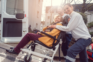 Wall Mural - Senior woman in wheelchair being picked up by team from transport service