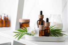Essential Oils, Green Leaves And Orchid Flower On White Shelf In Bathroom