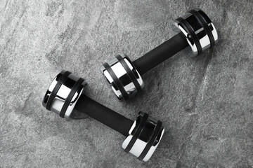 Two dumbbells on grey background, flat lay