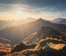 Wall Mural - aerial view of man on the hill and beautiful mountains in haze at colorful sunset in autumn. dolomit