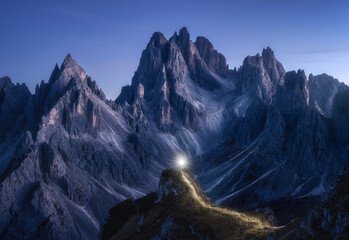 Wall Mural - Flashlight trails on mountain path against high rocks at night in autumn. Tre cime, Dolomites, Italy. Colorful landscape with light trails, trail on the hill, mountain peaks, sky with stars in fall 