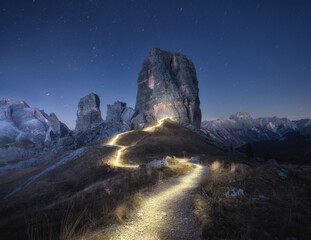 Wall Mural - Flashlight trails on mountain path against high rocks at night in autumn. Dolomites, Italy. Colorful landscape with light trails, trail on the hill, alpine mountain peaks, sky with stars in fall 