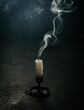 © Cavan Images - Smoke coming from a blown out candle on the floor of a dark room.