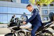 © Cavan Images - businessman in full suit is sitting on the motorbike outdoors