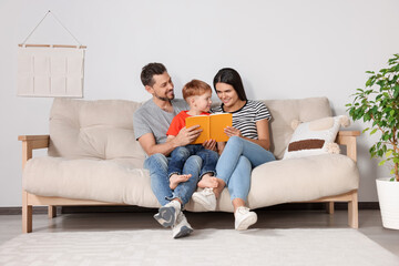 Wall Mural - Happy family reading book together on sofa in living room at home