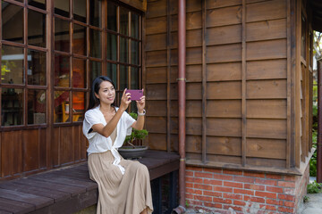 Poster - Woman sit outside Japanese wooden house and use mobile phone to take photo