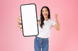 © sitthiphong - Studio shot of Beautiful Asian woman holding smartphone mockup of blank screen and smiling isolated on pink background.
