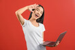 © Johnstocker - Portrait of a happy asian businesswoman working on laptop computer isolated over red background