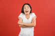© Johnstocker - Portrait of Excited young asian woman in white t-shirt crossed arm isolated on red background