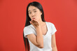 © Johnstocker - Portrait of Young asian woman in white t-shirt sending kiss and looking at camera isolated on red background