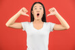 © Johnstocker - Portrait of Excited young asian woman in white t-shirt showing thumbs up isolated on red background