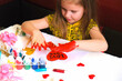 Child making homemade greeting card. A little girl paints a hearts as a gift for Mother’s Day or VAlentines day. Traditional play concept. Arts and crafts concept.