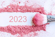 Flat lay of smear of crushed pink blush on as sample of cosmetics product with 2023 number, copy space, top view. Happy new year concept	