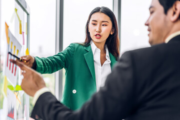 Casual creative happy two smile asian business people plan strategy analysis and brainstorm putting post it sticker note to share idea for startup project on glass board at modern office