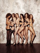 © Serge Lee - Six beautiful women in black lingerie on wall background. Loft style portrait of girls group in underwear. Female models posing in sexy outfit at loft studio.