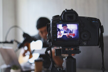Asian Influencer Playing Guitar During Podcast Or Live Video Broadcast For The Audience From The Camera At Home