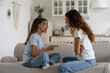 © DimaBerlin - Mother and teen daughter arguing while sitting in front of each other on sofa at home, stressed mom trying to cope with adolescent behavior, parent dealing with issues of adolescence
