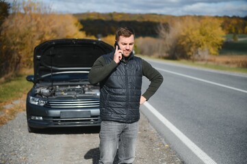 Wall Mural - A man calls a phone number to talk to a mechanic. The car broke down on the roadside. The concept for fix, help, problem, repair. blurred background.