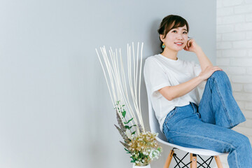 Canvas Print - 椅子に座って考えるおしゃれなジーンズ姿の日本人女性
